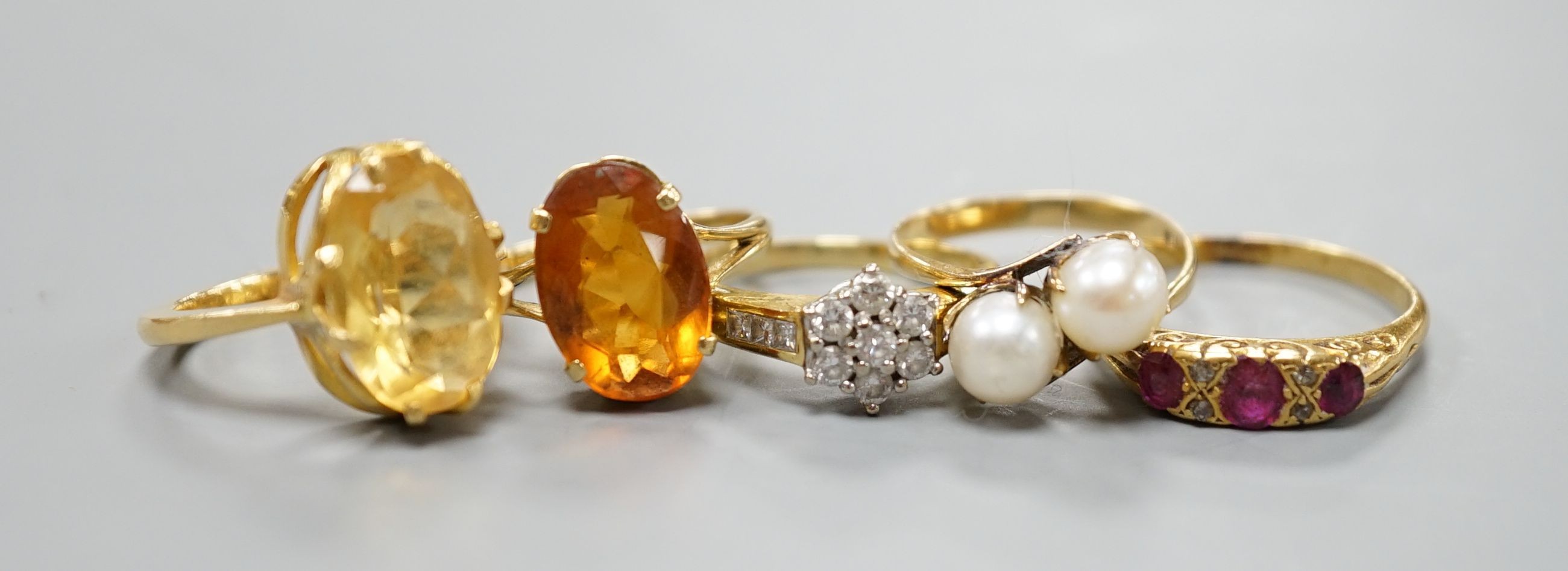 Five assorted gold and gold coloured metal dress rings, comprising a two stone cultured pearl stamped 18k, size L, an 18ct gold diamond cluster, size L, an unmarked citrine?, an 18ct orange stone, size L and an early 20t